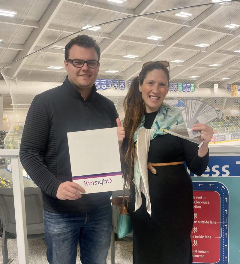 Tali Campbell with a community member giving a thumbs up at the arena with event tickets.