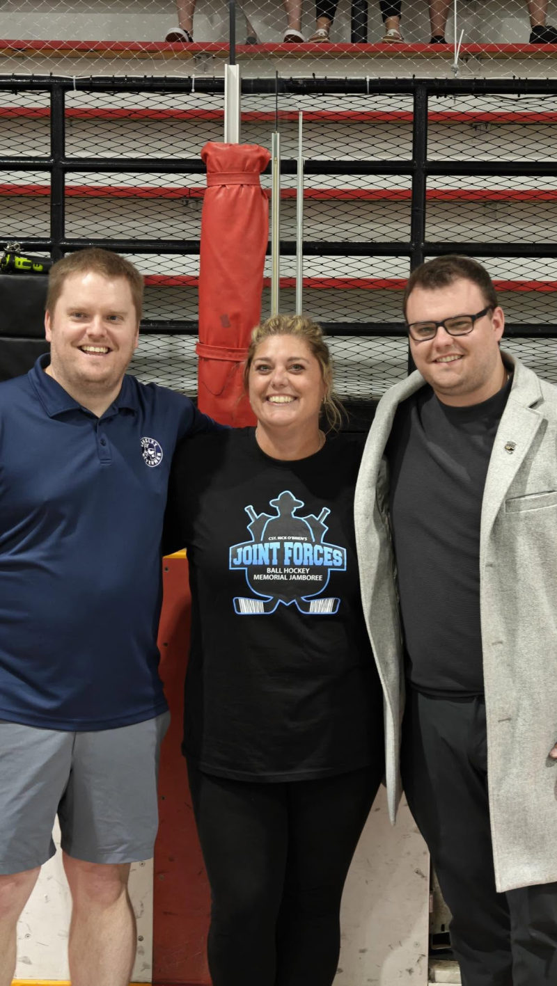 Tali Campbell with community members at the Joint Forces Ball Hockey Memorial Jamboree in an arena.